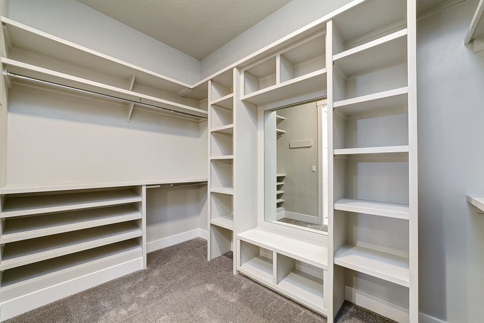 Mid-sized arts and crafts gender-neutral walk-in wardrobe in Boise with open cabinets, white cabinets, carpet and grey floor.