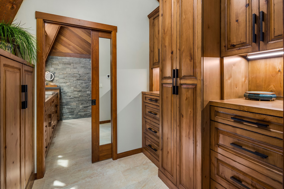 This is an example of a mid-sized country gender-neutral walk-in wardrobe in Seattle with raised-panel cabinets, medium wood cabinets and porcelain floors.