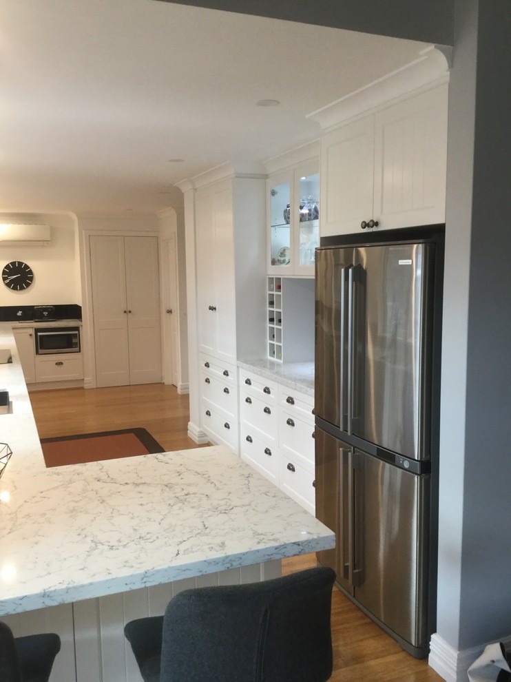 Inspiration for a large transitional u-shaped kitchen pantry in Perth with an undermount sink, shaker cabinets, white cabinets, quartz benchtops, black splashback, glass sheet splashback, stainless steel appliances, medium hardwood floors and no island.