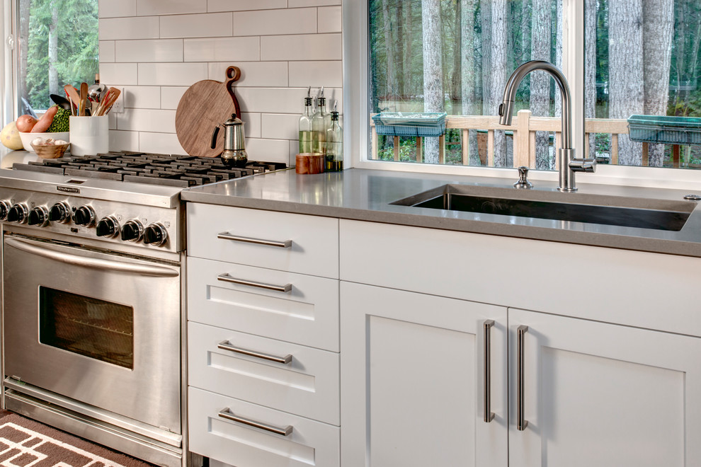 Open concept kitchen - transitional l-shaped medium tone wood floor open concept kitchen idea in Seattle with an undermount sink, shaker cabinets, white cabinets, quartz countertops, white backsplash, subway tile backsplash, stainless steel appliances and an island