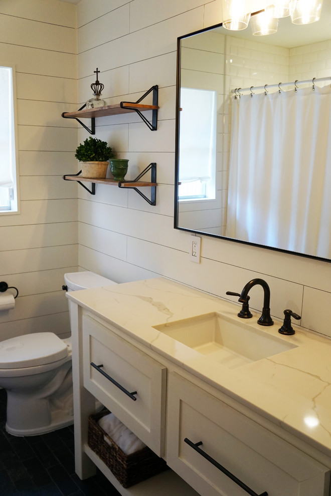 This is an example of a mid-sized scandinavian 3/4 bathroom in Houston with furniture-like cabinets, white cabinets, an alcove tub, a shower/bathtub combo, white walls, slate floors, an undermount sink, marble benchtops, black floor, a shower curtain, a two-piece toilet, white tile and subway tile.