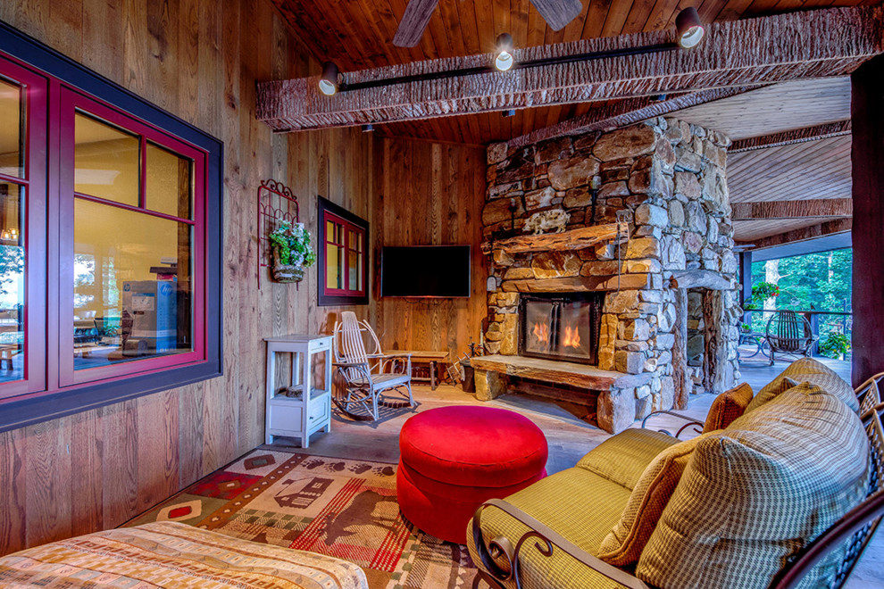 This is an example of a large rustic back porch design with a fireplace, decking and a roof extension.