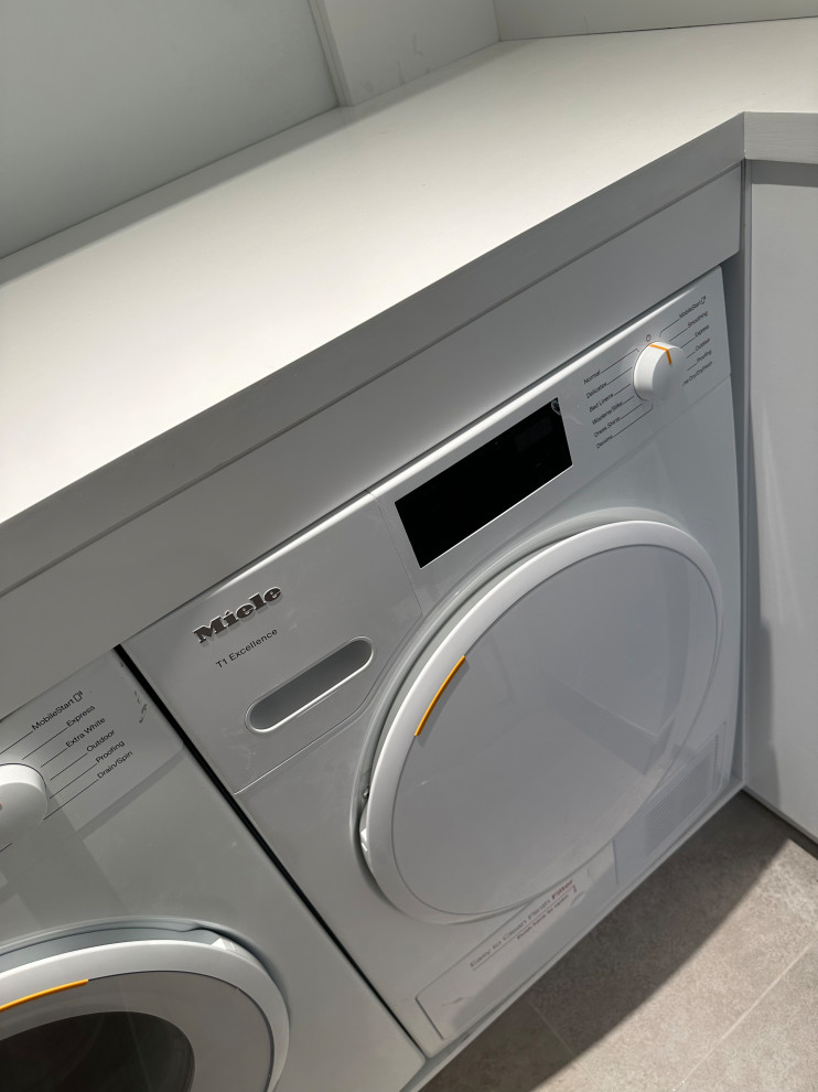 This is an example of a small modern single-wall laundry cupboard in Other with open cabinets, white cabinets, wood worktops, white walls, slate flooring, a side by side washer and dryer, grey floors and white worktops.