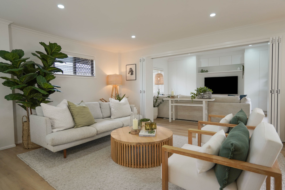 Стильный дизайн: гостиная комната в морском стиле с светлым паркетным полом и телевизором на стене - последний тренд