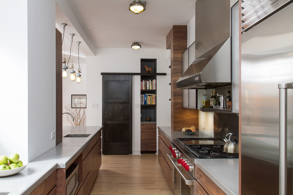 Design ideas for a transitional galley kitchen in Chicago with flat-panel cabinets, dark wood cabinets, metallic splashback, stainless steel appliances, an undermount sink and concrete benchtops.