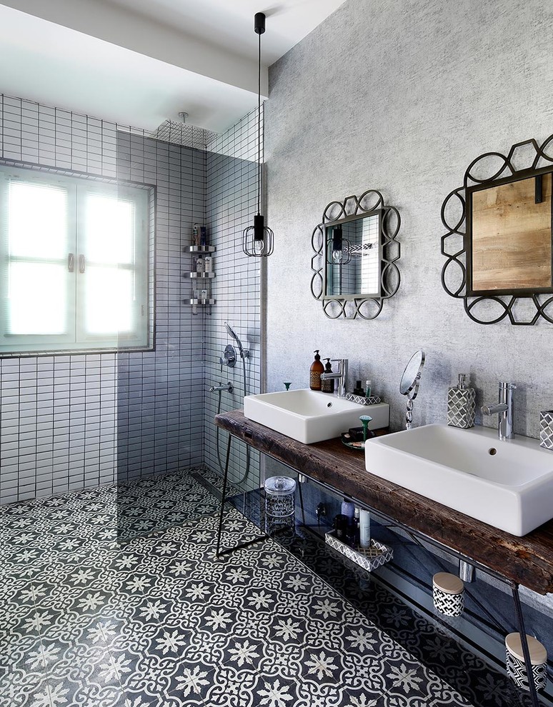 Photo of a mediterranean master bathroom in Other with an open shower, a one-piece toilet, black and white tile, ceramic tile, grey walls, a console sink, wood benchtops, open cabinets and an open shower.