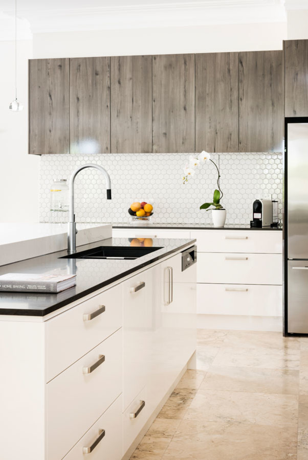 Design ideas for an expansive modern l-shaped open plan kitchen in Melbourne with an undermount sink, flat-panel cabinets, light wood cabinets, quartz benchtops, white splashback, mosaic tile splashback, black appliances, marble floors, with island and pink floor.