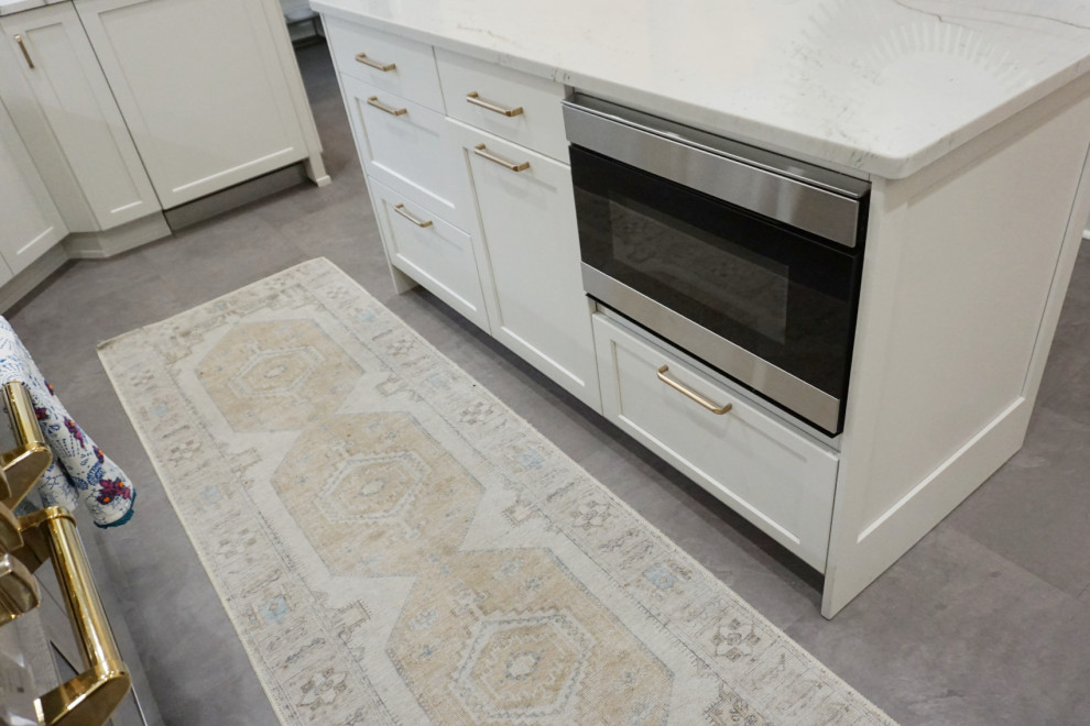 Example of a transitional vinyl floor and gray floor kitchen design with an undermount sink, shaker cabinets, gray cabinets, quartzite countertops, stone slab backsplash, stainless steel appliances and an island
