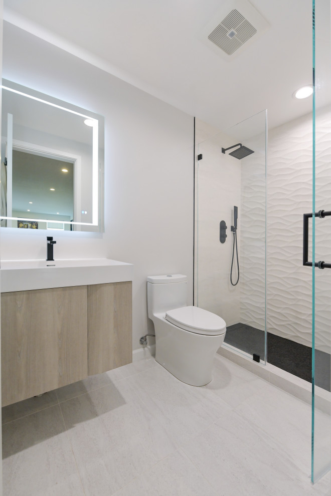 Источник вдохновения для домашнего уюта: ванная комната среднего размера в современном стиле с плоскими фасадами, светлыми деревянными фасадами, душем в нише, унитазом-моноблоком, белой плиткой, керамической плиткой, белыми стенами, полом из цементной плитки, душевой кабиной, монолитной раковиной, мраморной столешницей, серым полом, душем с распашными дверями, белой столешницей, тумбой под одну раковину, подвесной тумбой и панелями на части стены