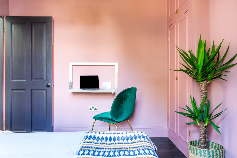 This is an example of a mid-sized eclectic guest bedroom in London with pink walls, dark hardwood floors, no fireplace and brown floor.