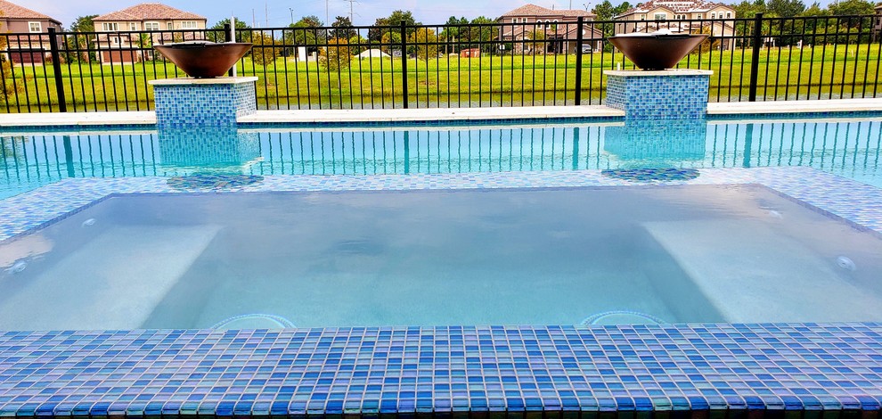 Photo of a mid-sized modern rectangular lap pool in Orlando with a hot tub and natural stone pavers.