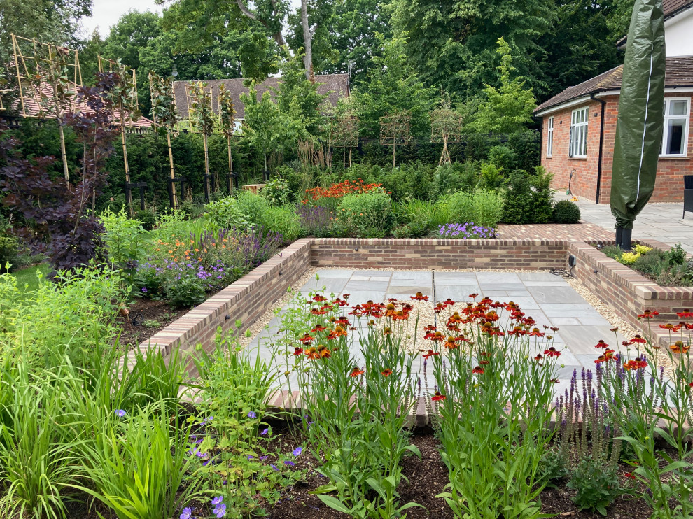 Immagine di un grande giardino design esposto in pieno sole dietro casa in estate con pavimentazioni in pietra naturale