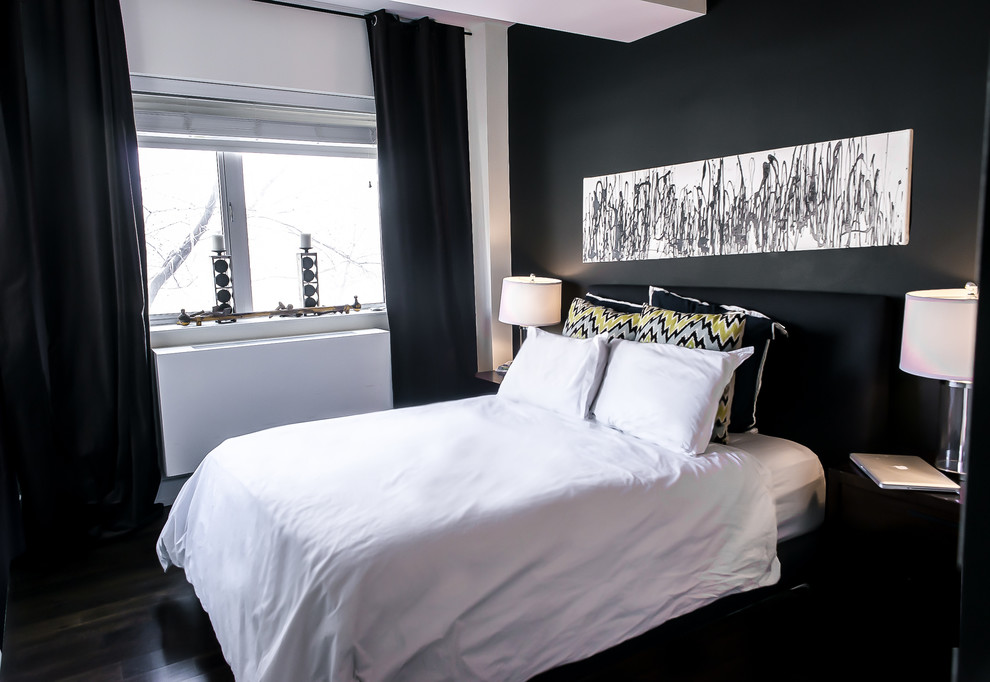 Photo of a mid-sized industrial loft-style bedroom in New York with black walls and medium hardwood floors.