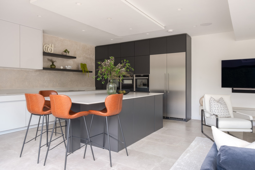 Design ideas for a large contemporary grey and white l-shaped open plan kitchen in Gloucestershire with flat-panel cabinets, quartz worktops, grey splashback, engineered quartz splashback, porcelain flooring, an island, beige floors and grey worktops.