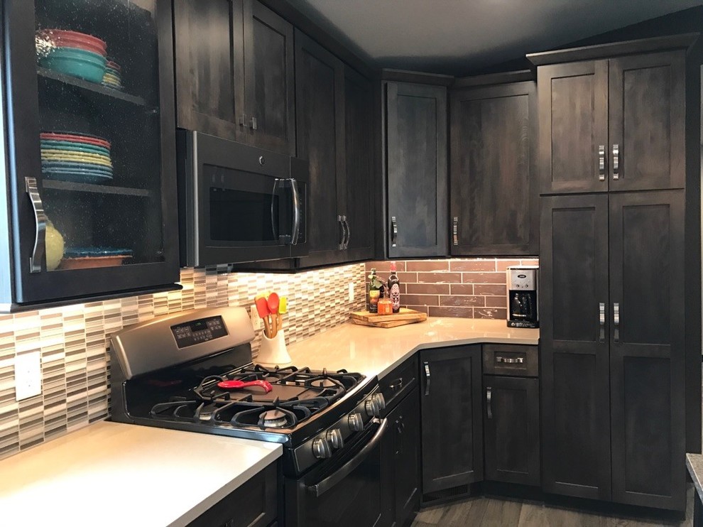 Open concept kitchen - mid-sized transitional single-wall light wood floor and brown floor open concept kitchen idea with shaker cabinets, dark wood cabinets, multicolored backsplash, glass tile backsplash, stainless steel appliances, an island, a farmhouse sink and granite countertops