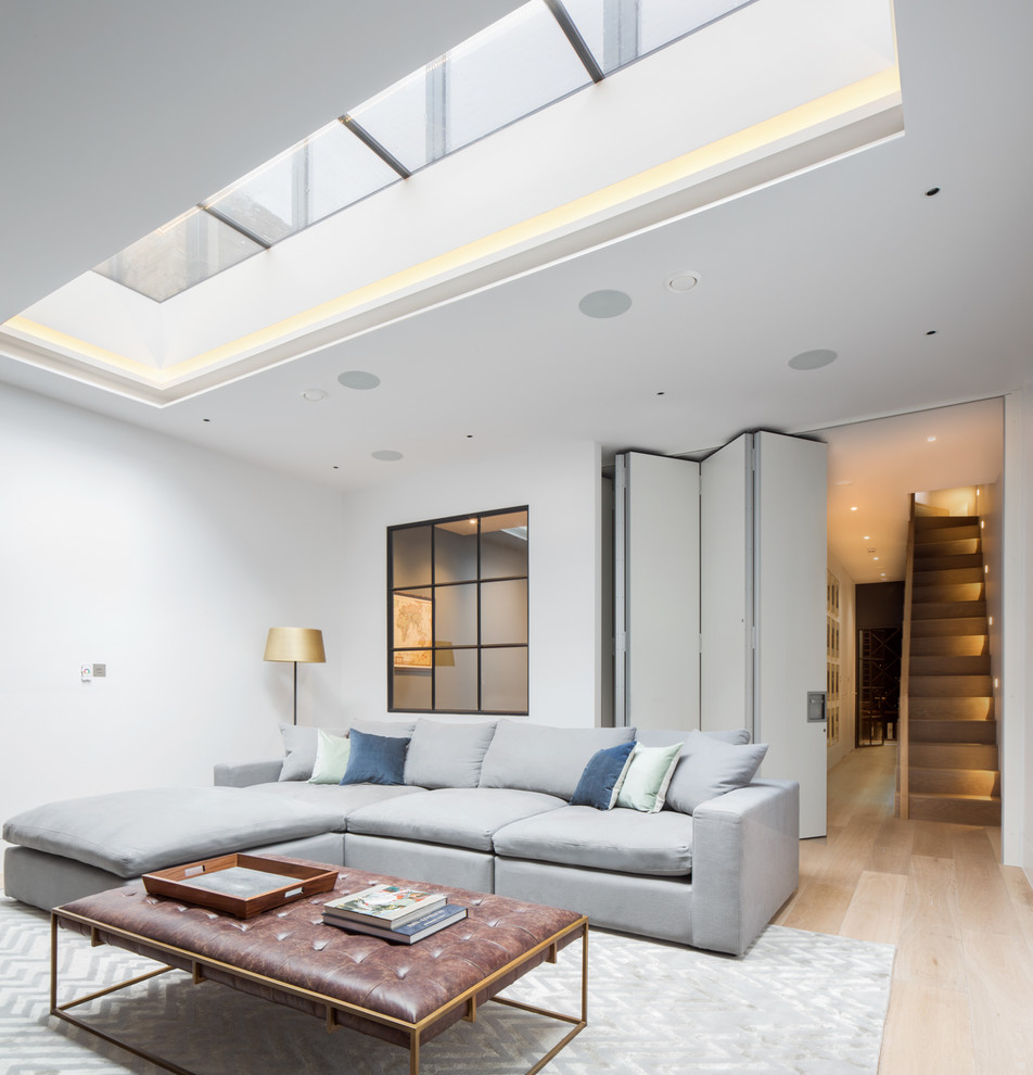 Inspiration for a mid-sized contemporary fully buried basement in London with white walls, light hardwood floors and beige floor.