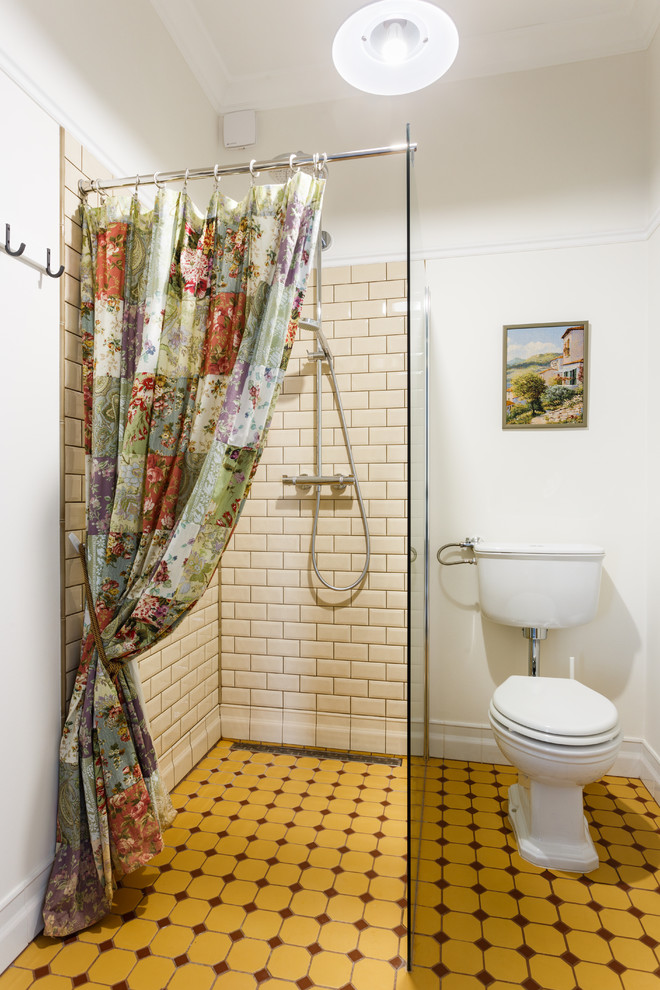 Photo of a small country 3/4 bathroom in Other with raised-panel cabinets, white cabinets, a curbless shower, a two-piece toilet, beige tile, ceramic tile, beige walls, porcelain floors, a console sink, yellow floor and an open shower.