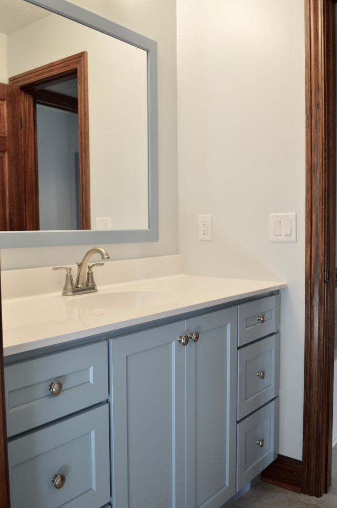 This is an example of a mid-sized transitional bathroom with shaker cabinets, blue cabinets, an alcove tub, a two-piece toilet, blue walls, laminate floors, an integrated sink, onyx benchtops, beige floor, white benchtops, a single vanity and a built-in vanity.