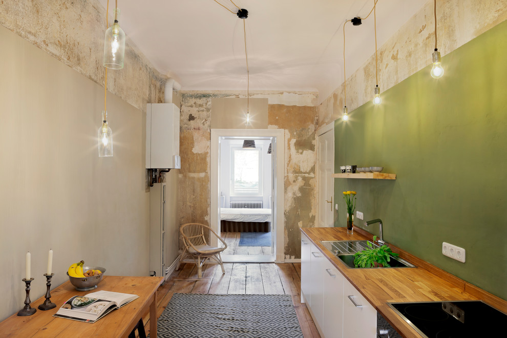 Photo of a mid-sized industrial single-wall eat-in kitchen in Berlin with a drop-in sink, wood benchtops, green splashback and medium hardwood floors.