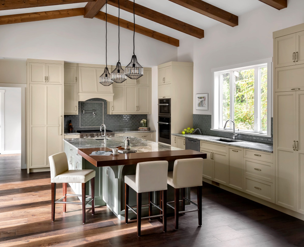 Eat-in kitchen - large transitional l-shaped dark wood floor, brown floor and exposed beam eat-in kitchen idea in Other with a single-bowl sink, shaker cabinets, beige cabinets, granite countertops, blue backsplash, glass tile backsplash, paneled appliances, an island and multicolored countertops
