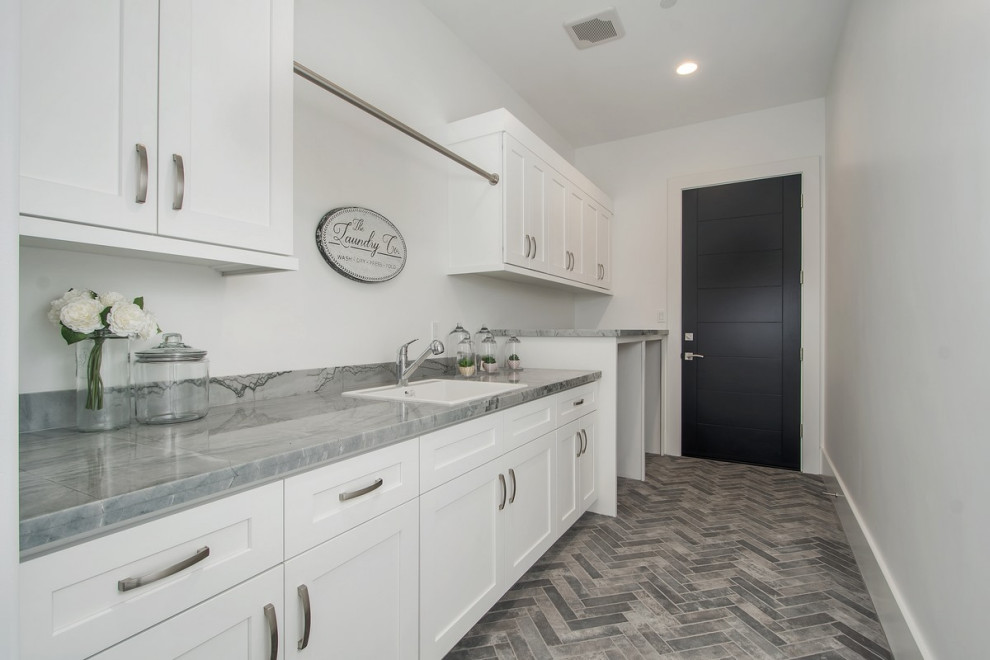 Design ideas for a large contemporary single-wall laundry room in San Diego with a drop-in sink, recessed-panel cabinets, white cabinets, quartzite benchtops, white walls, brick floors, a side-by-side washer and dryer, grey floor and grey benchtop.