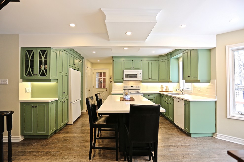 Inspiration for a large beach style separate kitchen in Toronto with an undermount sink, recessed-panel cabinets, green cabinets, quartz benchtops, white splashback, ceramic splashback, white appliances, vinyl floors, with island and brown floor.