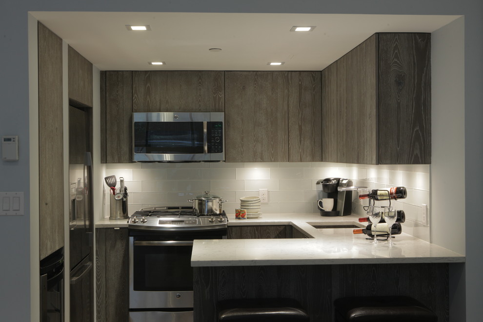 Design ideas for a mid-sized contemporary u-shaped separate kitchen in New York with an undermount sink, flat-panel cabinets, grey cabinets, terrazzo benchtops, white splashback, glass tile splashback, stainless steel appliances and a peninsula.