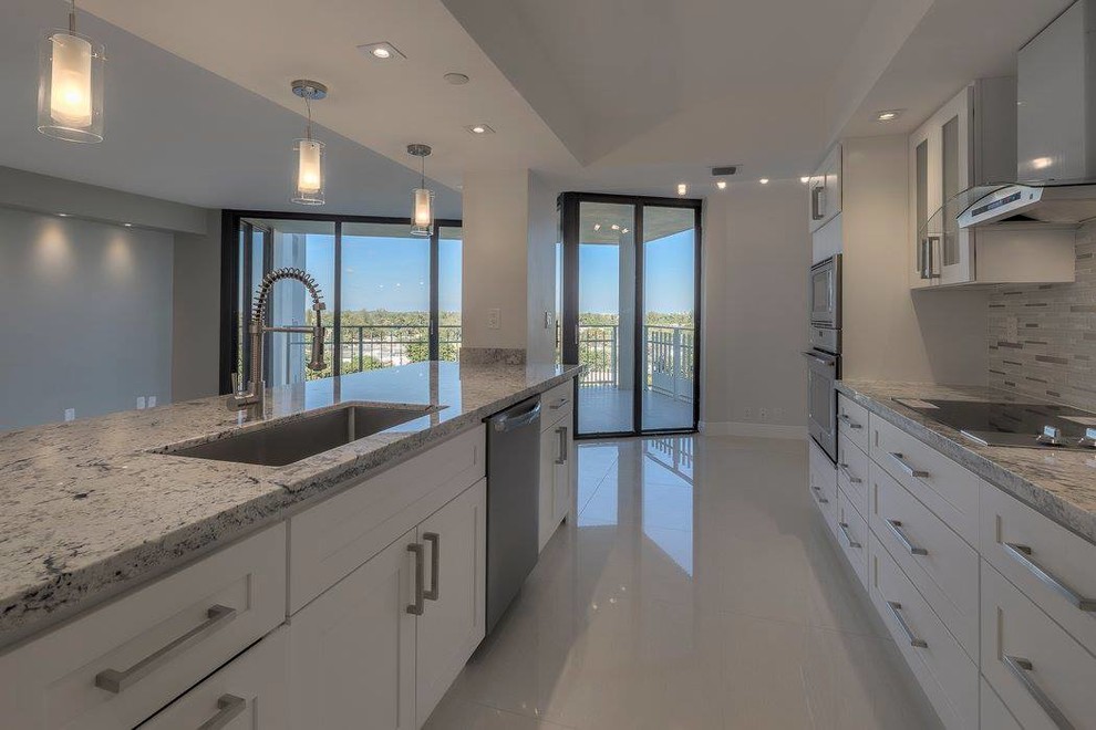 Large modern single-wall eat-in kitchen in Miami with an undermount sink, shaker cabinets, white cabinets, granite benchtops, multi-coloured splashback, matchstick tile splashback, stainless steel appliances, porcelain floors and with island.