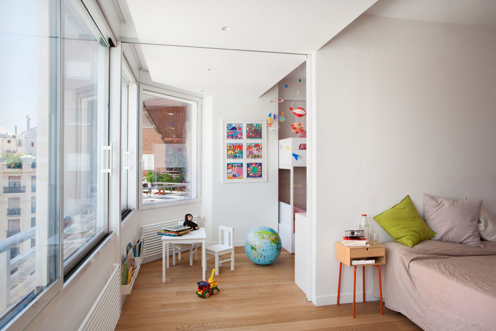 Photo of a small scandinavian gender-neutral kids' room in Madrid with white walls and light hardwood floors.