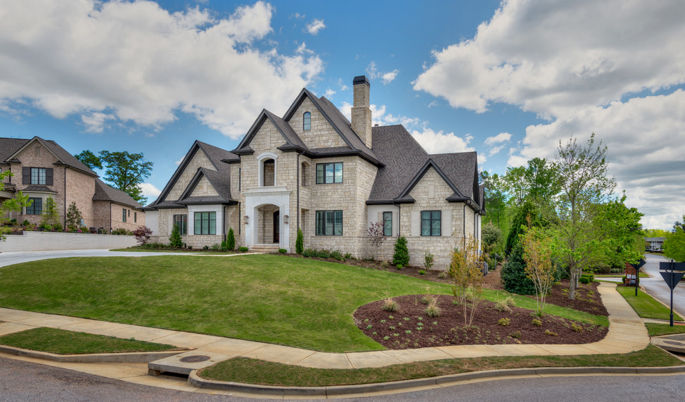 Inspiration for a large transitional beige two-story stone gable roof remodel with a shingle roof
