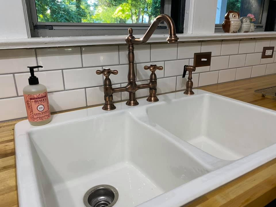This is an example of a traditional kitchen in Cleveland with a double-bowl sink, wood benchtops and subway tile splashback.