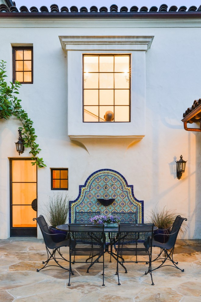 Large mediterranean backyard patio in Santa Barbara with natural stone pavers and no cover.
