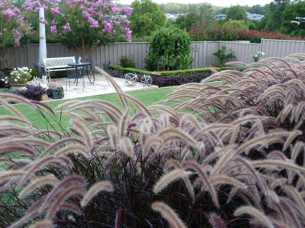 Large tropical backyard xeriscape in Sydney with concrete pavers.