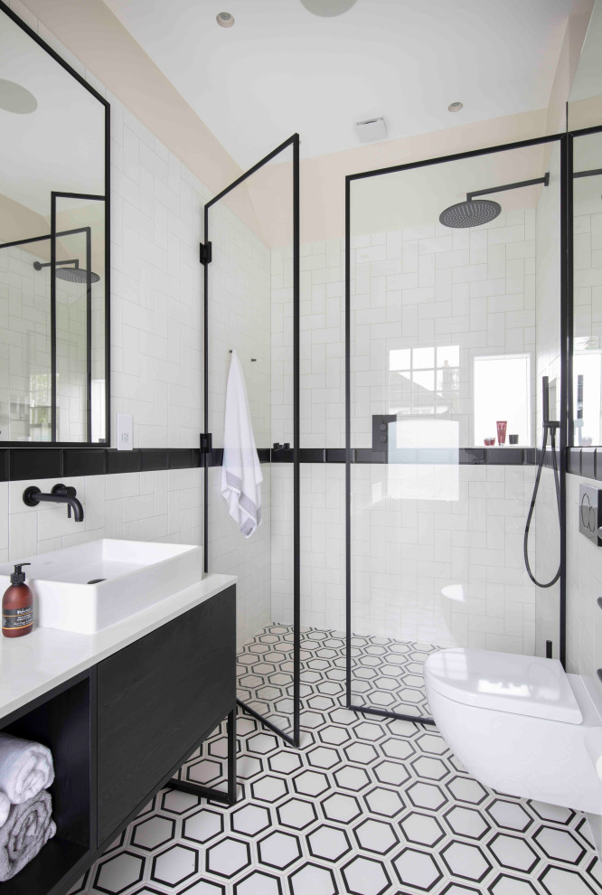 Photo of a mid-sized industrial master bathroom in Hertfordshire with flat-panel cabinets, black cabinets, an open shower, white tile, subway tile, granite benchtops, a hinged shower door and white benchtops.
