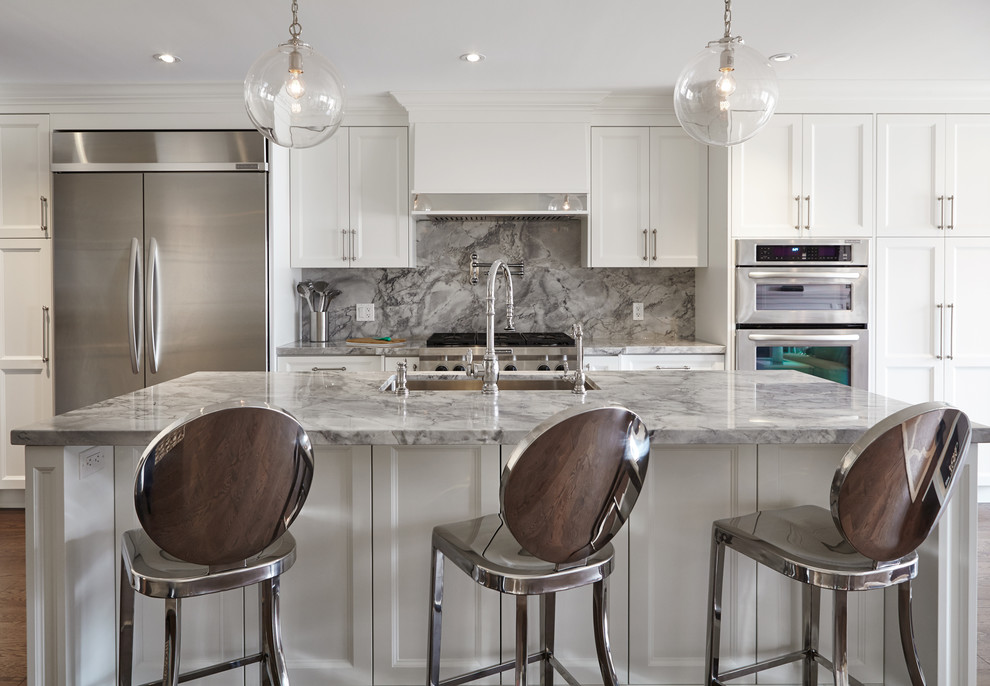 Photo of a mid-sized transitional single-wall open plan kitchen in Toronto with an undermount sink, beaded inset cabinets, white cabinets, marble benchtops, grey splashback, stone slab splashback, stainless steel appliances, medium hardwood floors and with island.