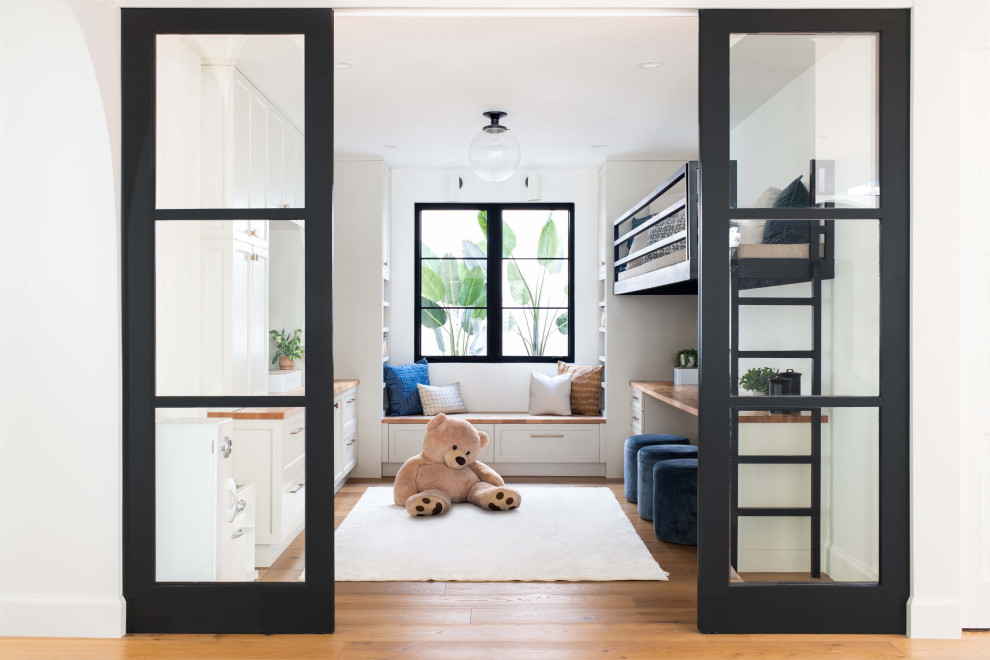 This is an example of a mid-sized mediterranean gender-neutral kids' room in Los Angeles with white walls, light hardwood floors and brown floor.