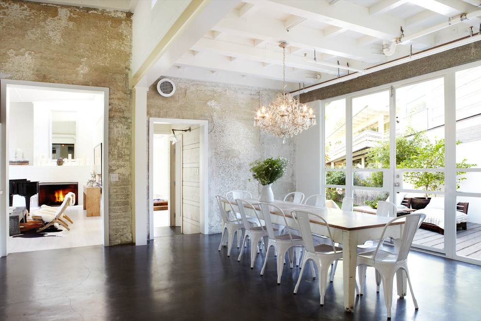 This is an example of a large industrial dining room in Orange County with beige walls, concrete floors, no fireplace and brown floor.