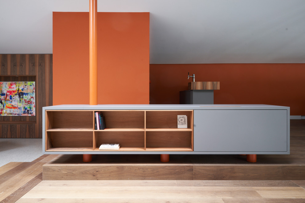Wohnzimmer mit oranger Wandfarbe, braunem Holzboden, Kamin, Kaminumrandung aus Beton und grauem Boden in Munich