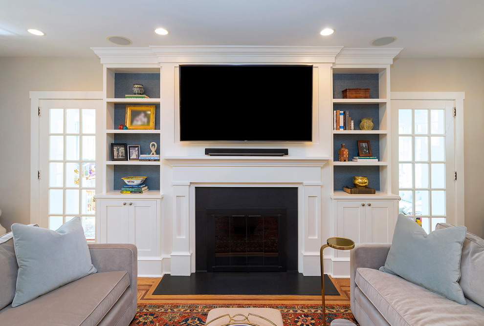 Design ideas for a mid-sized arts and crafts enclosed family room in Philadelphia with beige walls, medium hardwood floors, a standard fireplace, a wood fireplace surround, a wall-mounted tv and brown floor.