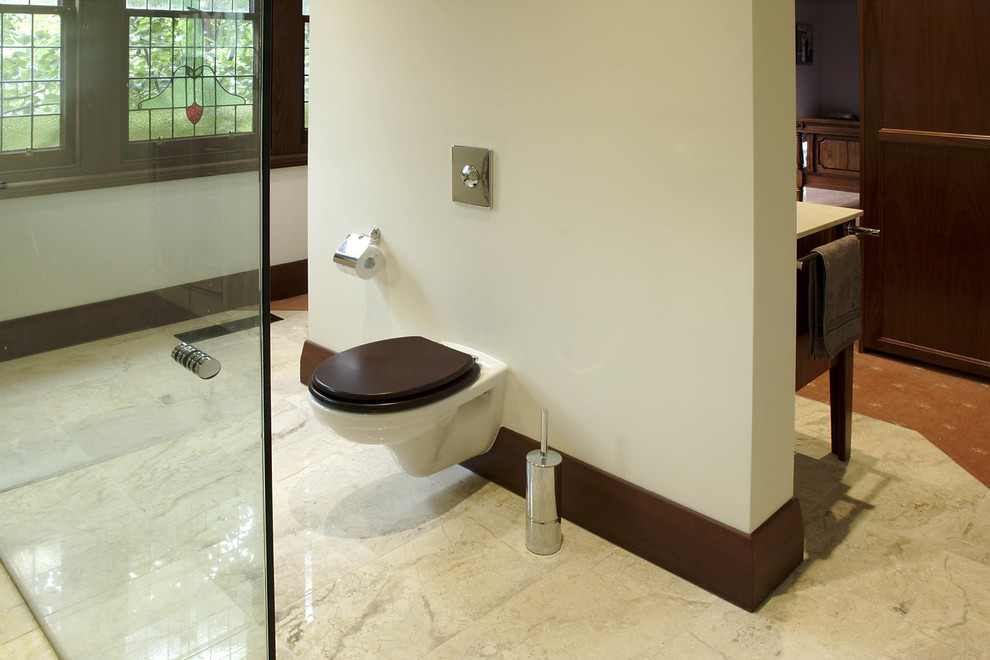 This is an example of an expansive traditional master bathroom in Melbourne with a wall-mount sink, furniture-like cabinets, medium wood cabinets, marble benchtops, a double shower, a wall-mount toilet, beige tile, stone tile, white walls and marble floors.