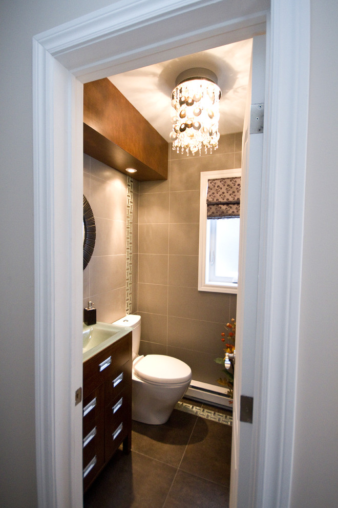 Design ideas for a small contemporary powder room in Montreal with flat-panel cabinets, dark wood cabinets, a two-piece toilet, beige tile, porcelain tile, beige walls, porcelain floors, an integrated sink and glass benchtops.
