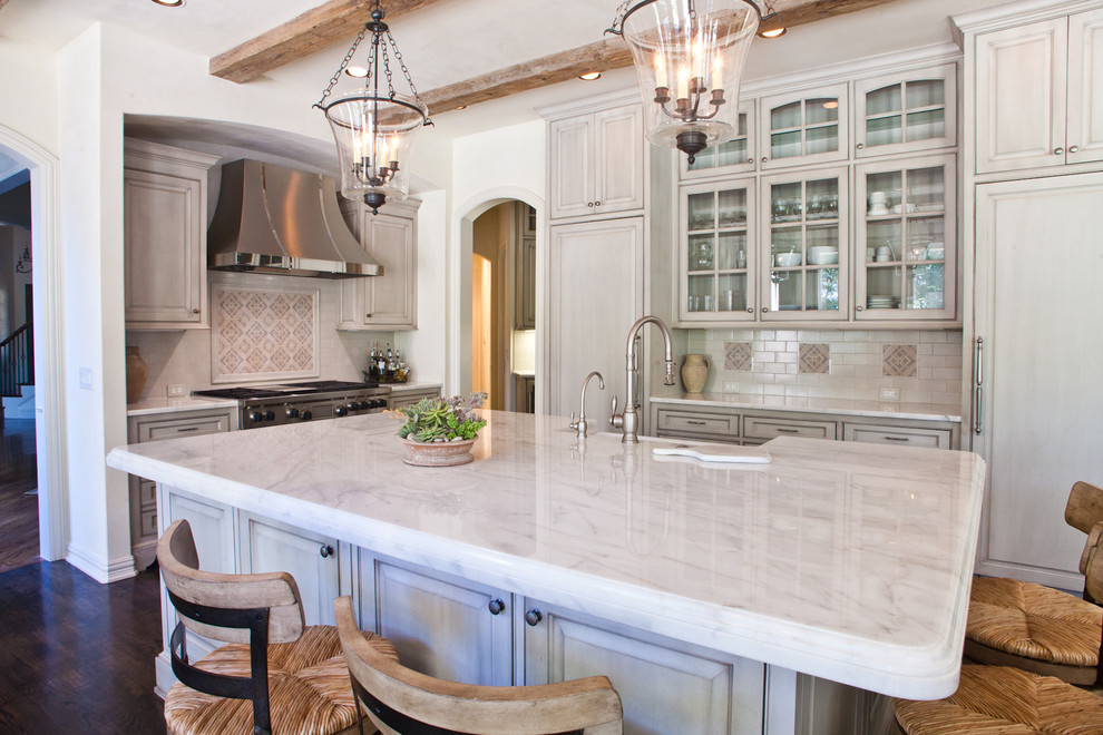 This is an example of a l-shaped kitchen in Dallas with a farmhouse sink, glass-front cabinets, grey cabinets, grey splashback, panelled appliances, dark hardwood floors and with island.