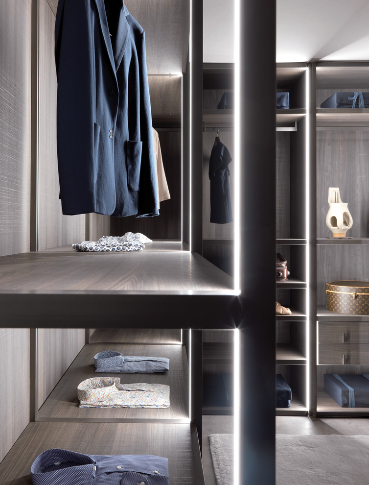 This is an example of a large contemporary gender-neutral walk-in wardrobe in Dorset with open cabinets, dark wood cabinets and concrete floors.