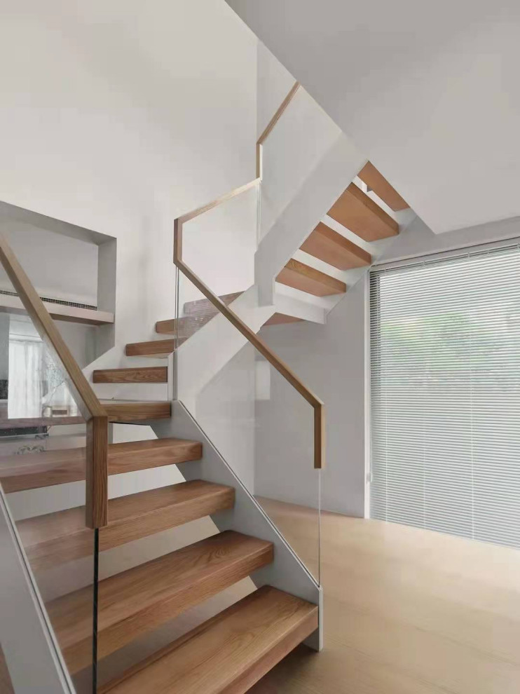 Exemple d'un escalier sans contremarche moderne en U de taille moyenne avec des marches en bois, un garde-corps en verre et du lambris.