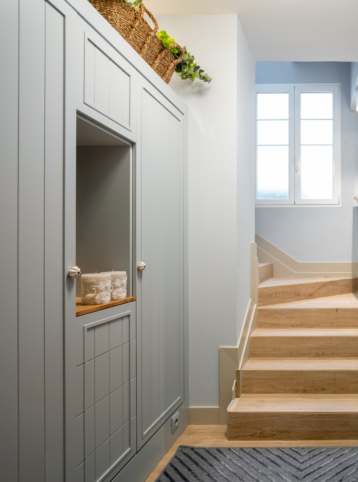 Design ideas for a small transitional mudroom in Other with blue walls, light hardwood floors, a single front door, a medium wood front door and brown floor.
