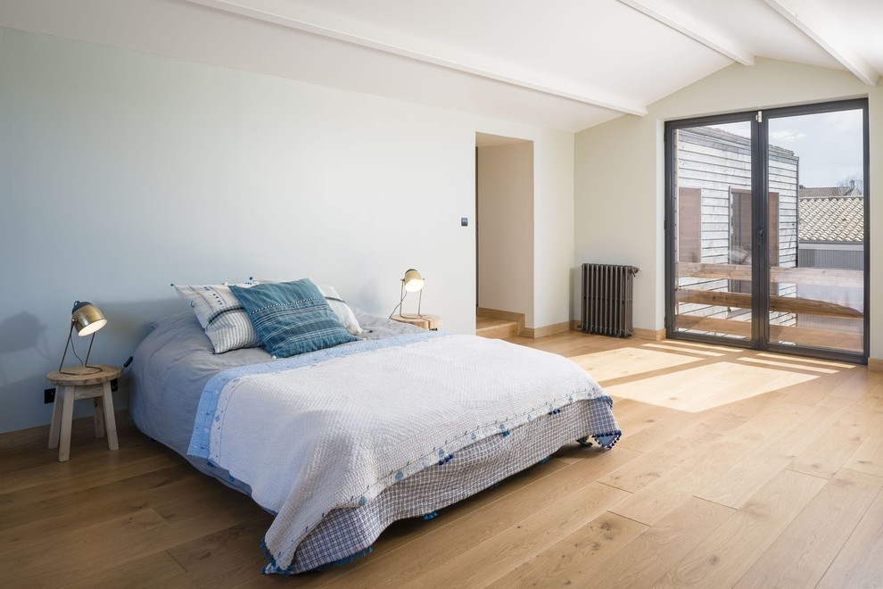 This is an example of a contemporary bedroom with white walls, medium hardwood floors and brown floor.
