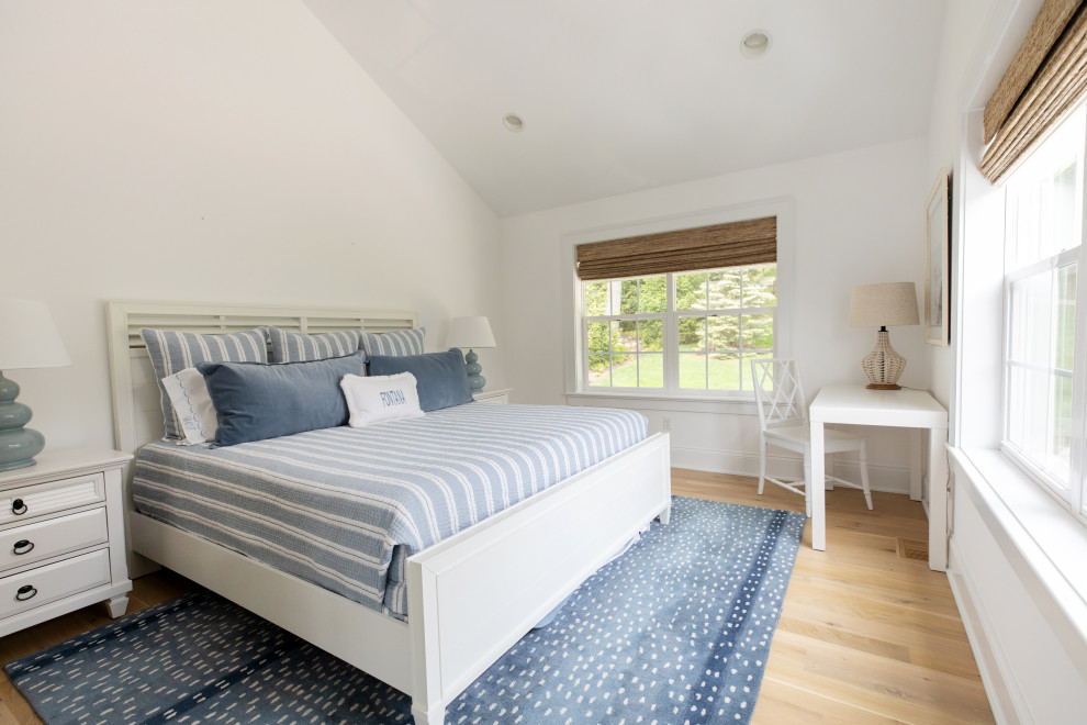 Immagine di una grande camera da letto stile marino con pareti bianche, parquet chiaro, cornice del camino in pietra e travi a vista