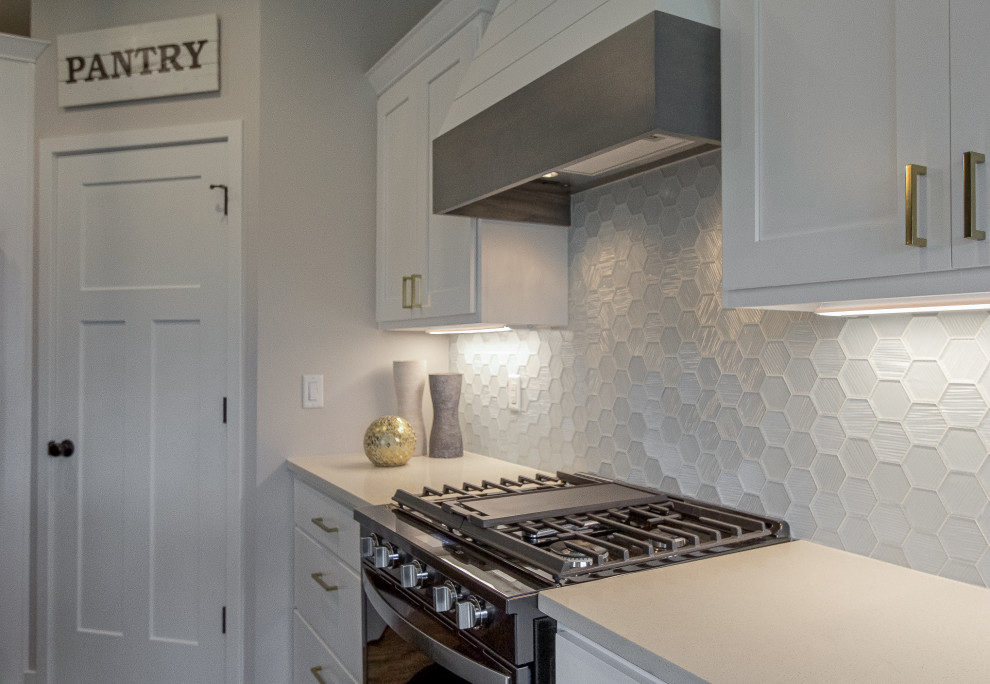 Large transitional l-shaped medium tone wood floor open concept kitchen photo with flat-panel cabinets, white cabinets, quartz countertops, white backsplash, glass tile backsplash, black appliances and beige countertops