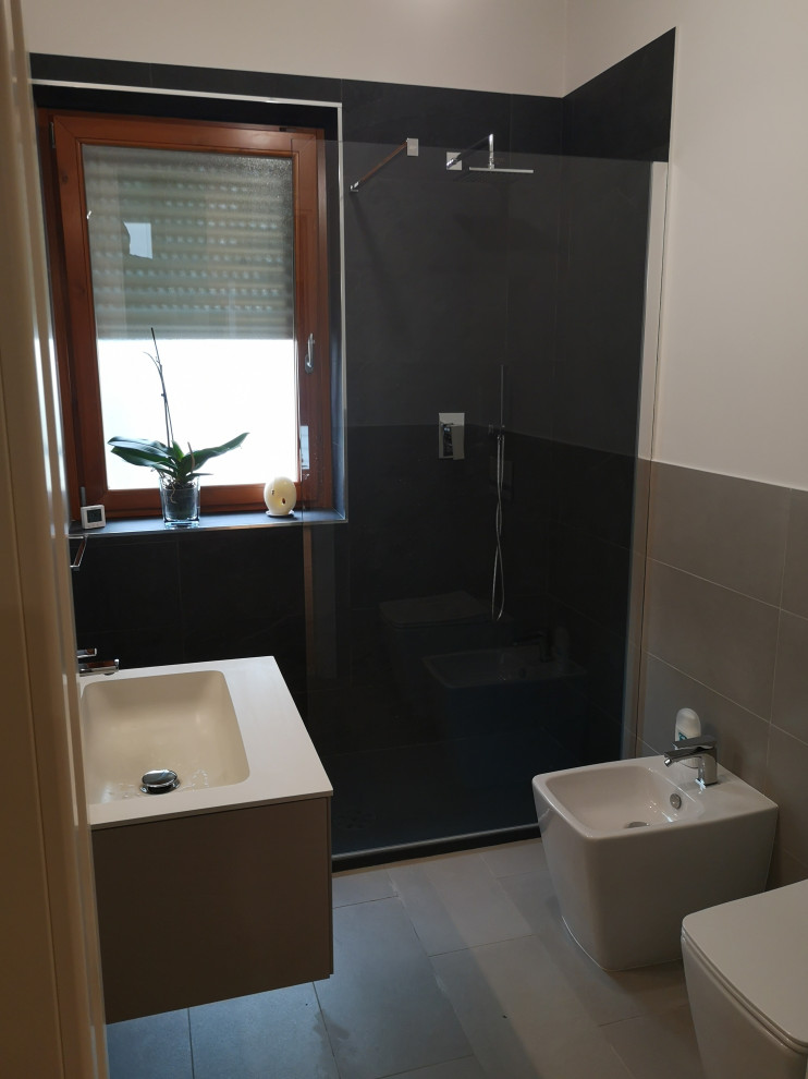 Inspiration for a small modern 3/4 bathroom in Turin with flat-panel cabinets, grey cabinets, a curbless shower, a two-piece toilet, gray tile, porcelain tile, white walls, porcelain floors, a console sink, solid surface benchtops, grey floor, an open shower and grey benchtops.