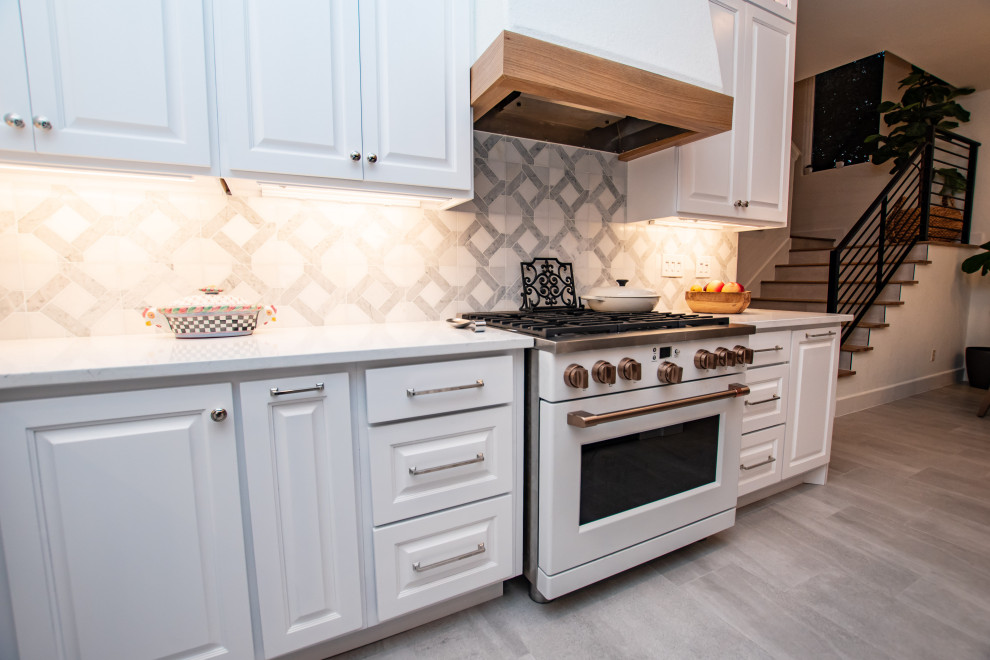 Example of a transitional l-shaped porcelain tile and gray floor eat-in kitchen design in Austin with an undermount sink, raised-panel cabinets, white cabinets, quartz countertops, white backsplash, marble backsplash, white appliances, an island and white countertops